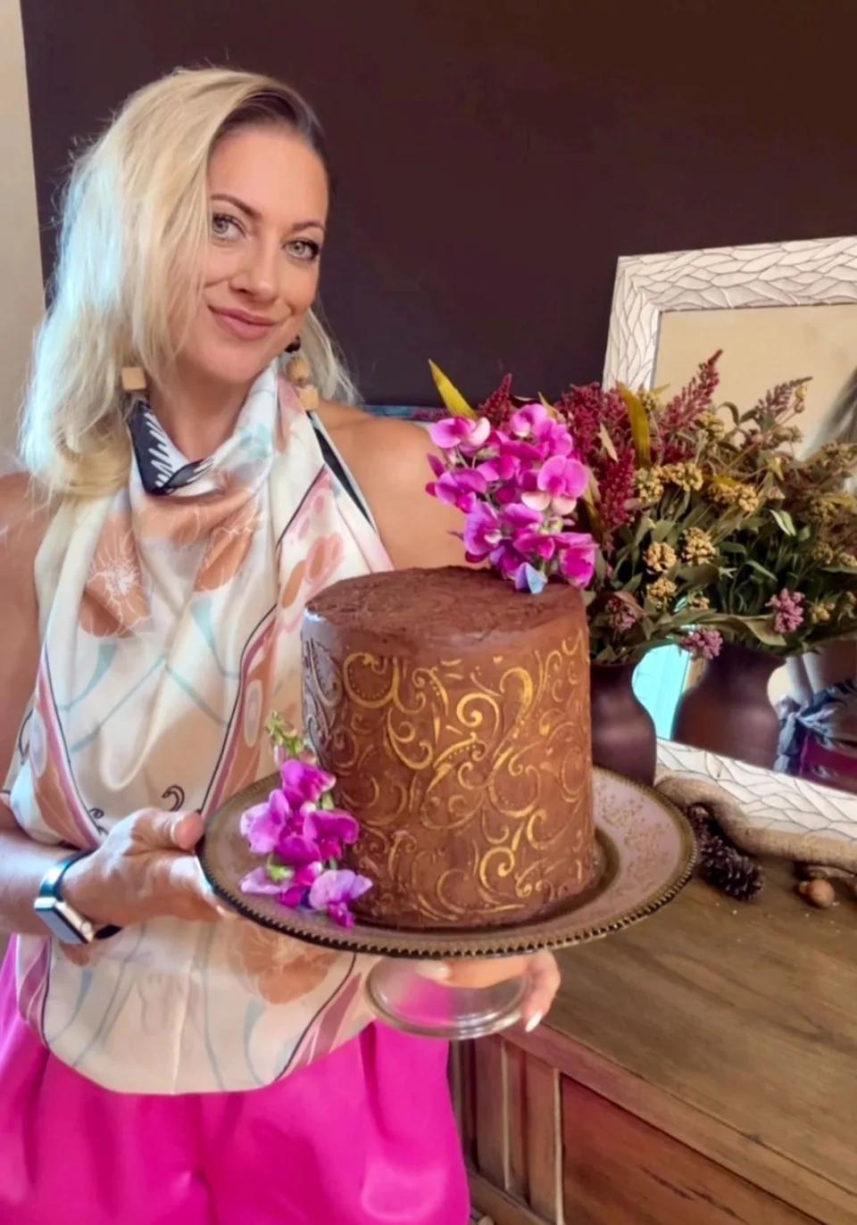 The baker with a chocolate cake and purple flowers