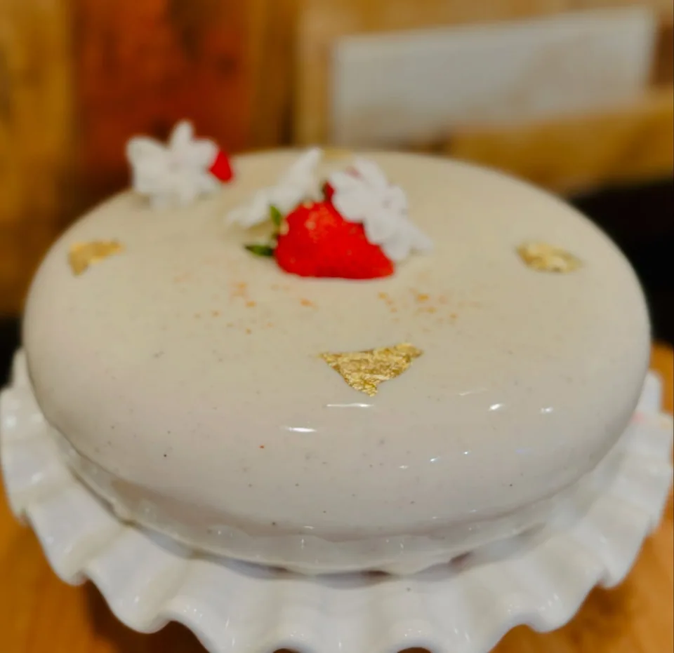 A white glazed cake with a red floral accent