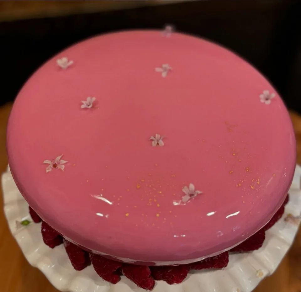 A smooth pink cake with small floral details